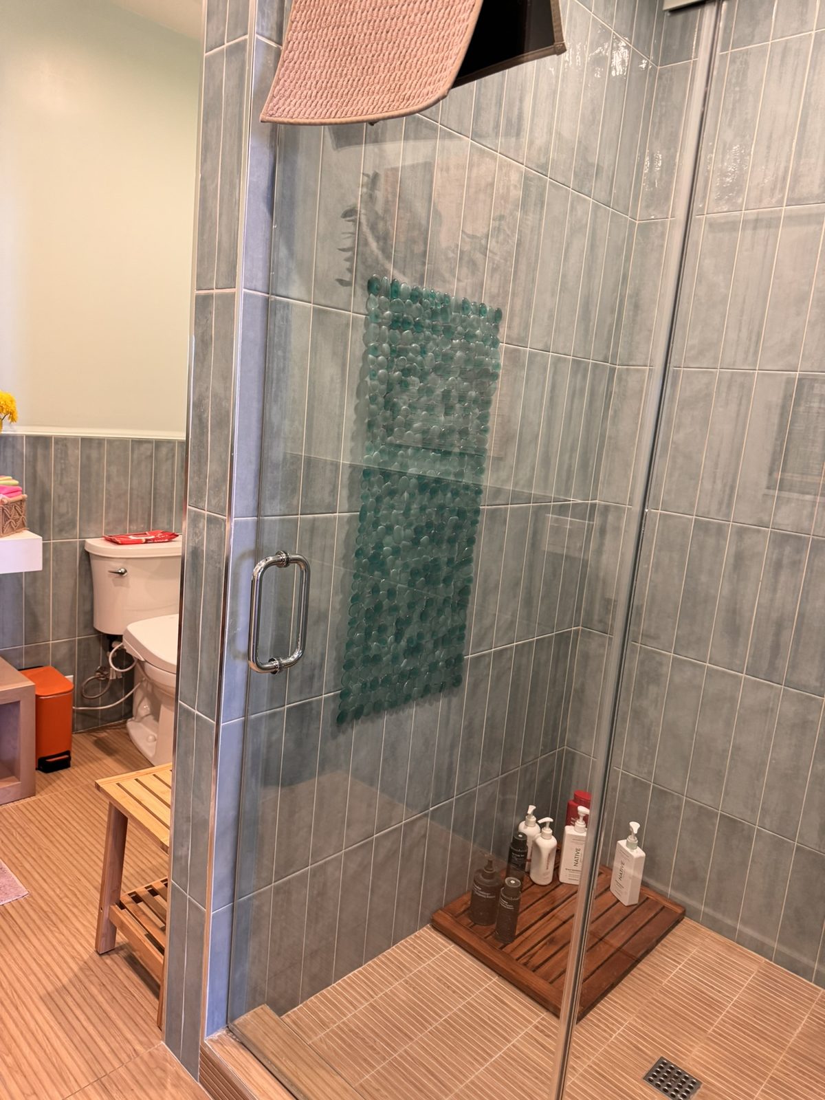 The bathroom at Lilley Fitness: a glass-walled tiled shower and a toilet with a bidet.
