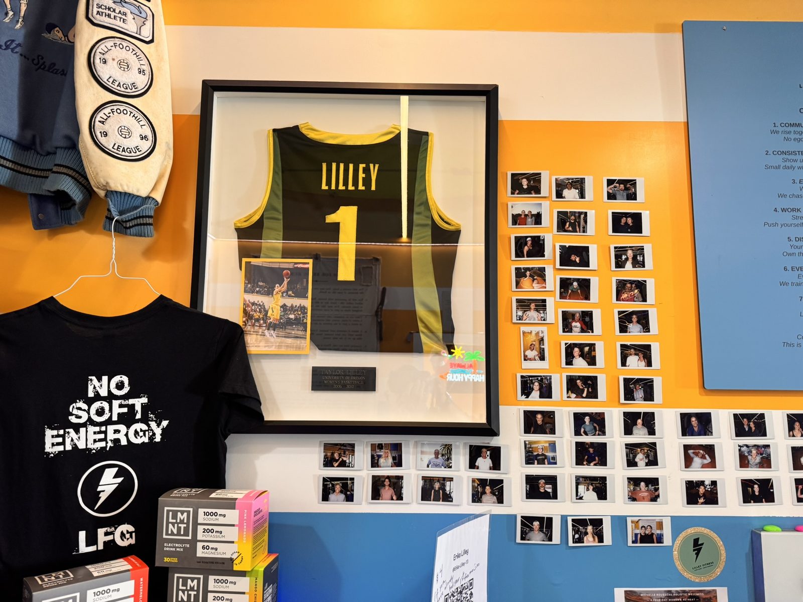 A framed Lilley number 1 jersey above a wall of member photos, beside a No Soft Energy LFG shirt.